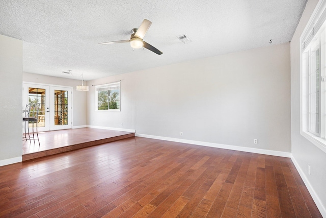 empty room featuring ceiling fan, french doors, hardwood / wood-style floors, and a textured ceiling