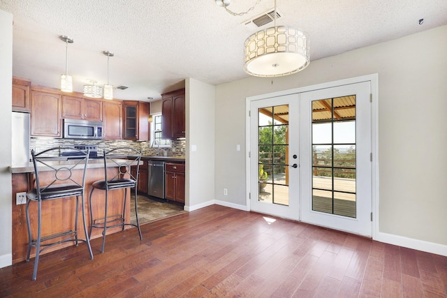 kitchen with visible vents, dark wood-type flooring, french doors, appliances with stainless steel finishes, and tasteful backsplash