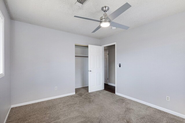 unfurnished bedroom with a textured ceiling, ceiling fan, a closet, and carpet