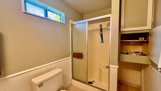 bathroom featuring an enclosed shower, tile patterned flooring, and toilet