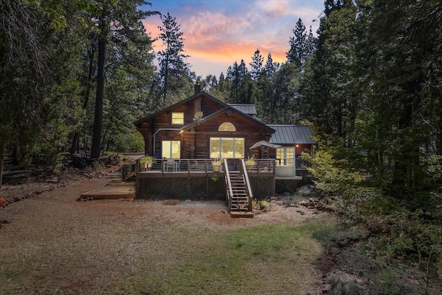 back of property featuring a deck, metal roof, stairs, a standing seam roof, and a view of trees