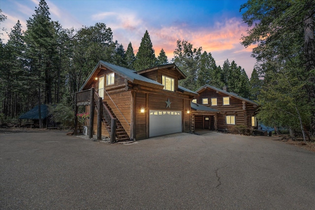 view of front of property featuring stairs, metal roof, aphalt driveway, and log siding