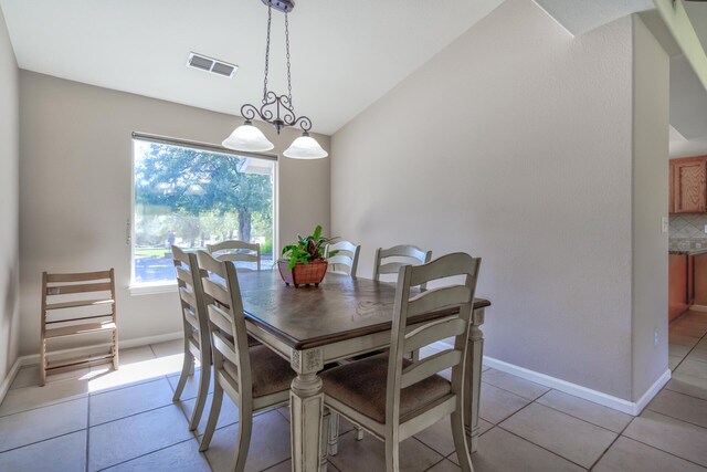 tiled dining area featuring lofted ceiling and an inviting chandelier