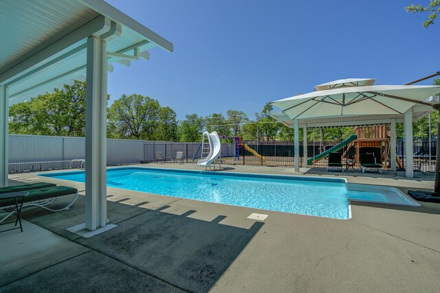 view of swimming pool with a water slide, a patio, and a playground