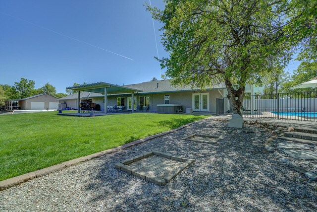 rear view of house featuring a fenced in pool, a patio area, and a lawn