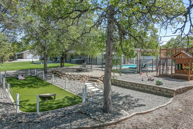 view of property's community with a lawn, a pool, and a playground