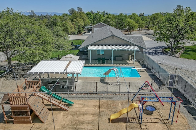 view of pool with a diving board, a patio area, a water slide, and a playground