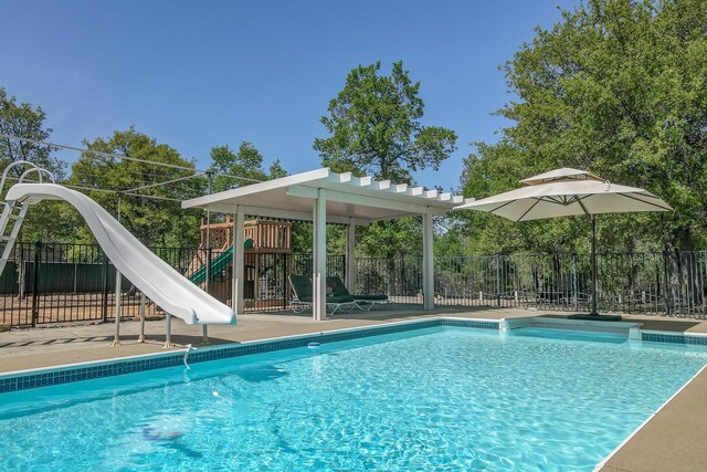 view of swimming pool featuring a water slide and a playground