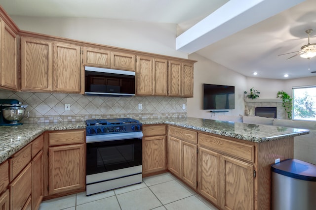 kitchen featuring light stone counters, stainless steel appliances, kitchen peninsula, and vaulted ceiling