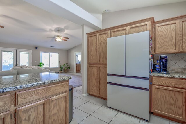 kitchen featuring white refrigerator, ceiling fan, light stone countertops, and vaulted ceiling