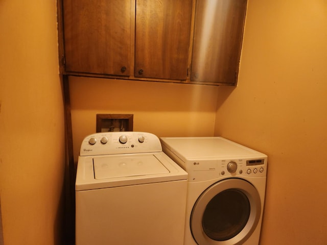 washroom with washing machine and clothes dryer and cabinets