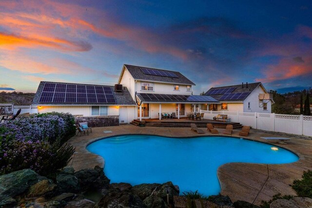 pool at dusk featuring a diving board and a patio