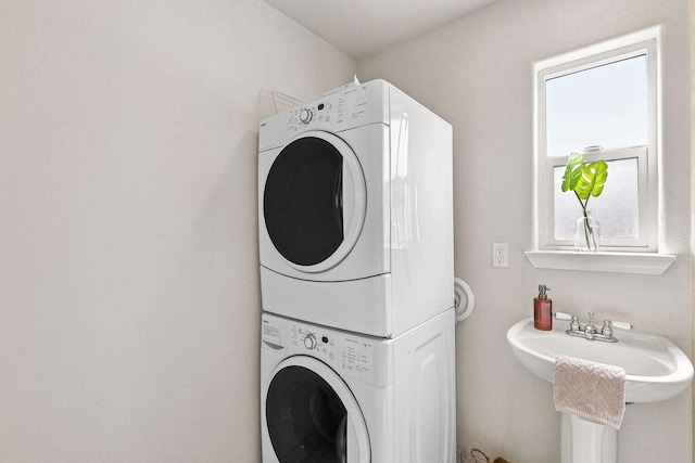 laundry area featuring plenty of natural light, sink, and stacked washer / dryer