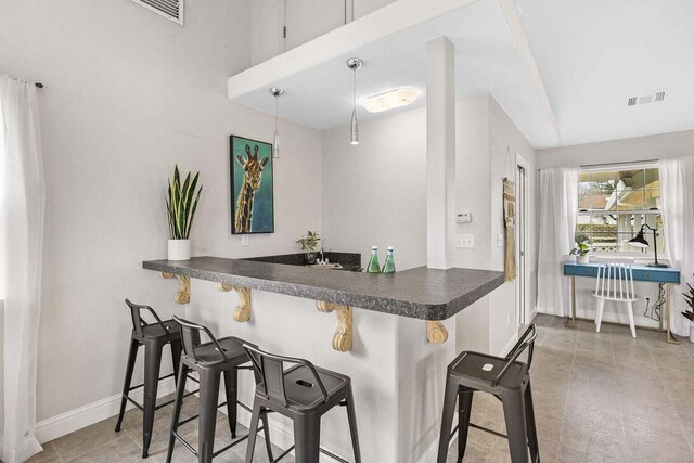 kitchen featuring a kitchen bar, decorative light fixtures, and kitchen peninsula