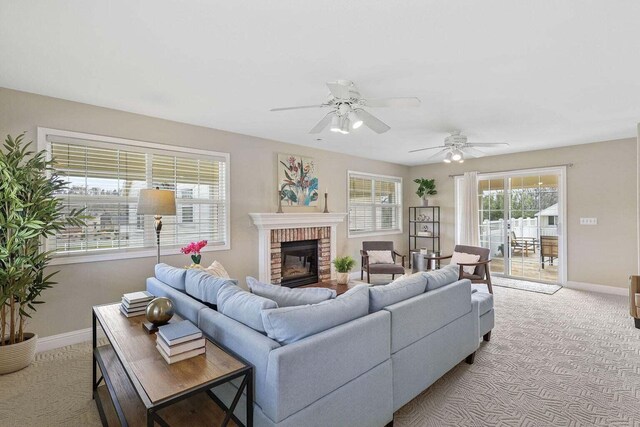 living room featuring a fireplace, light carpet, and ceiling fan