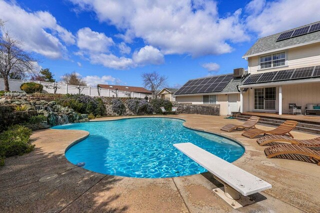 view of swimming pool with cooling unit, a diving board, and a patio