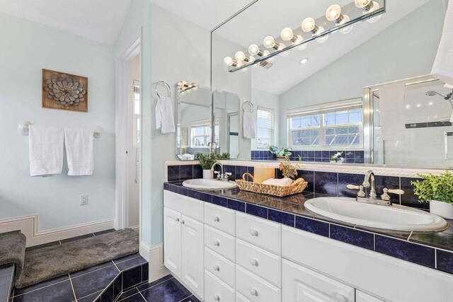 bathroom featuring lofted ceiling, tile patterned flooring, a shower with door, and vanity