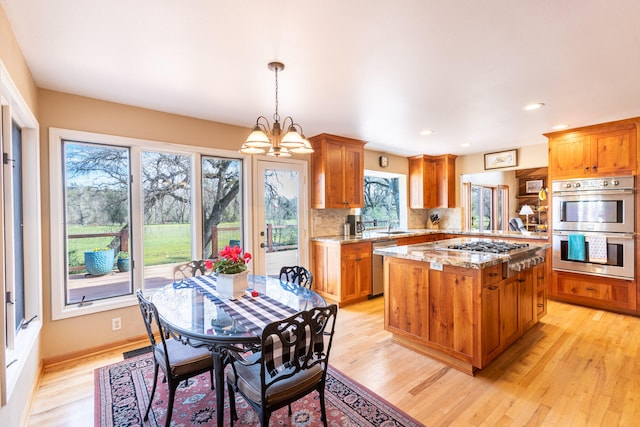 kitchen featuring backsplash, decorative light fixtures, a center island, light stone countertops, and appliances with stainless steel finishes