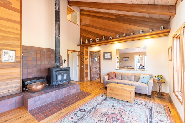 living room featuring beamed ceiling, wood-type flooring, high vaulted ceiling, and a wood stove