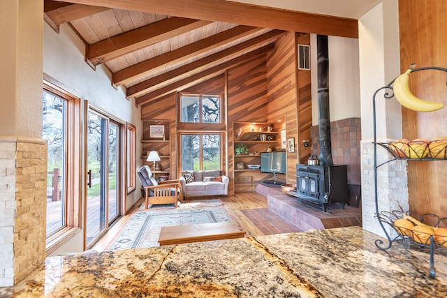 unfurnished living room with a wood stove, wood-type flooring, built in features, high vaulted ceiling, and beam ceiling