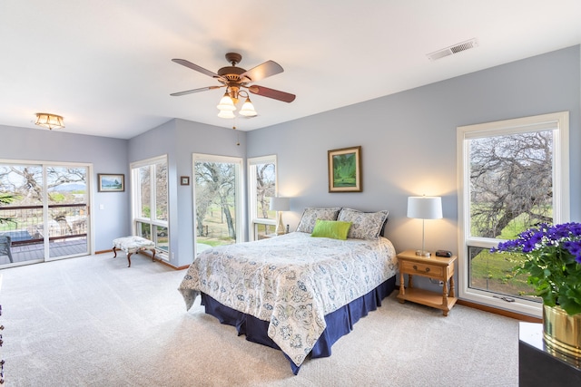 carpeted bedroom with access to exterior, ceiling fan, and multiple windows