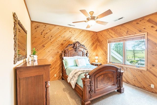 bedroom featuring crown molding, wood walls, ceiling fan, and carpet