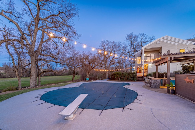 pool at dusk with a lawn, a diving board, a patio, and a pergola