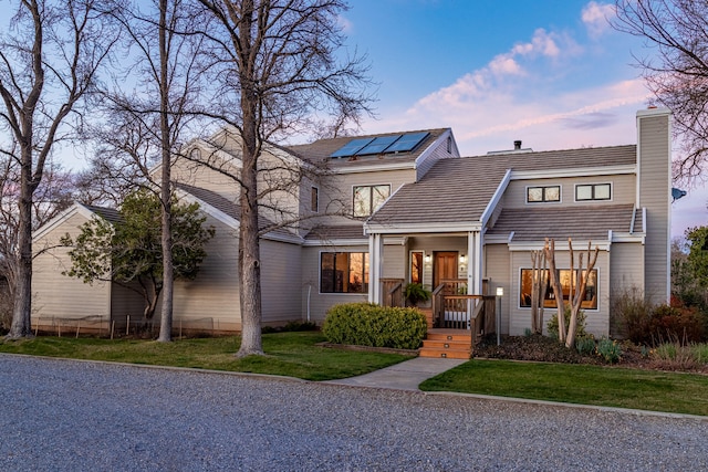 view of front of property with a lawn and solar panels