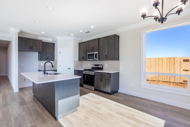 kitchen with pendant lighting, sink, crown molding, appliances with stainless steel finishes, and light wood-type flooring