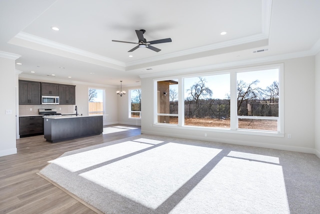 living room featuring ornamental molding, a tray ceiling, and light hardwood / wood-style flooring