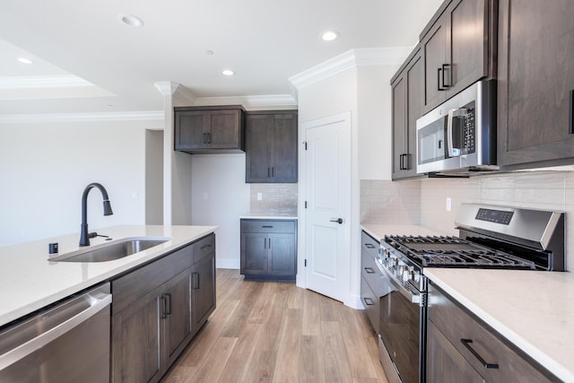 kitchen with sink, light wood-type flooring, ornamental molding, and appliances with stainless steel finishes