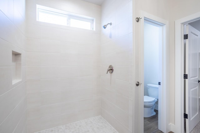 bathroom with a tile shower and toilet