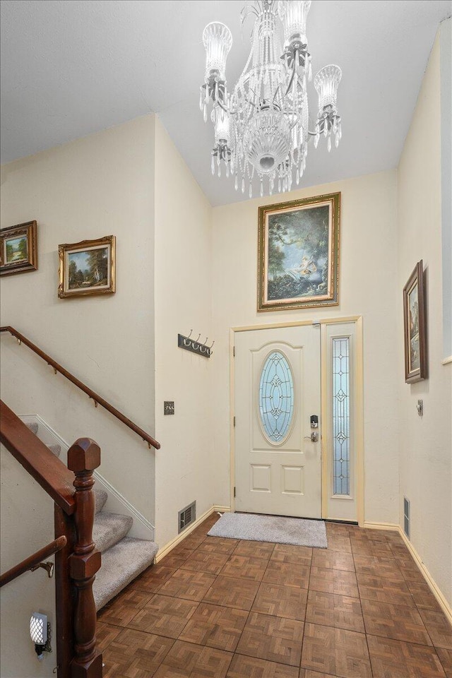 foyer entrance with an inviting chandelier and dark parquet flooring