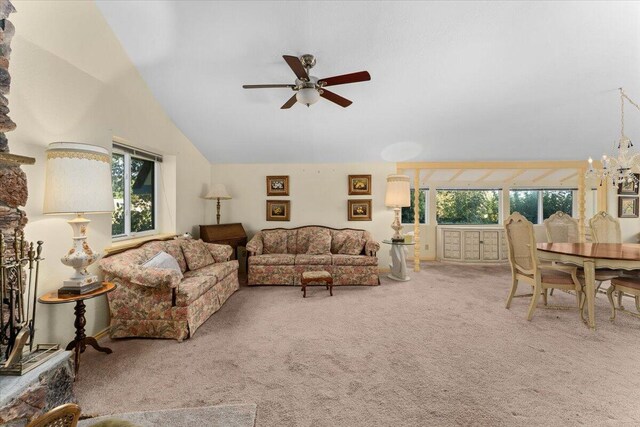 living room featuring ceiling fan with notable chandelier, vaulted ceiling, a healthy amount of sunlight, and carpet flooring