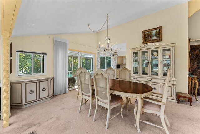 dining room featuring light colored carpet, an inviting chandelier, and vaulted ceiling