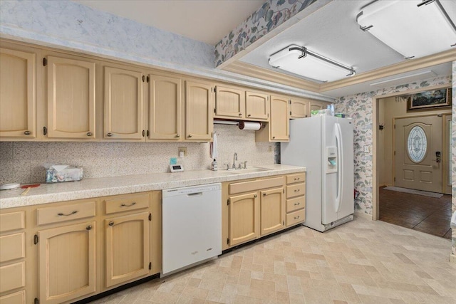 kitchen with white appliances, light brown cabinetry, and sink