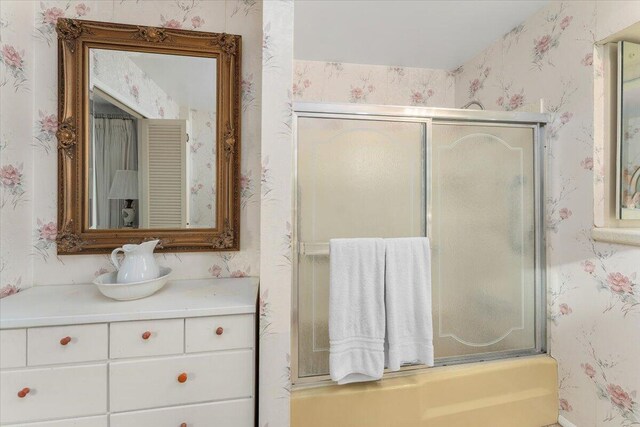 bathroom featuring vanity and bath / shower combo with glass door