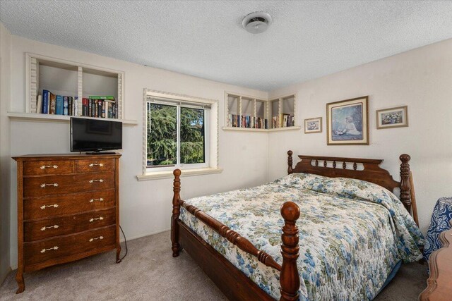 bedroom with a textured ceiling and light carpet