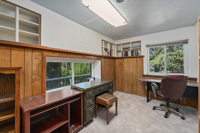 carpeted home office featuring wooden walls and a textured ceiling