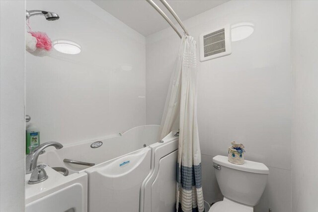 bathroom featuring shower / bath combo with shower curtain and toilet