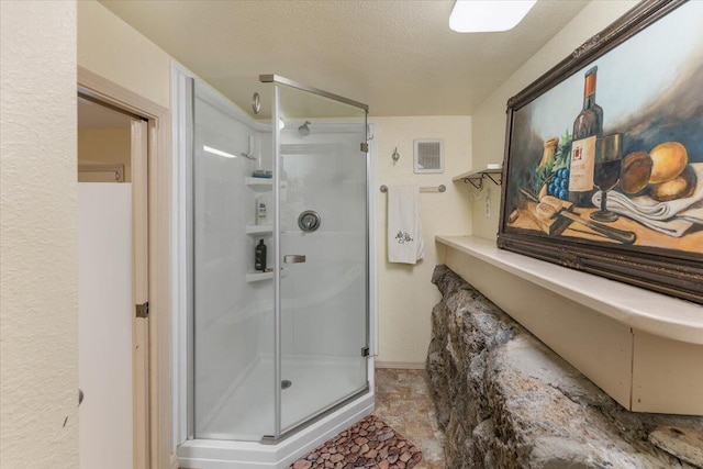 bathroom featuring a textured ceiling and a shower with shower door