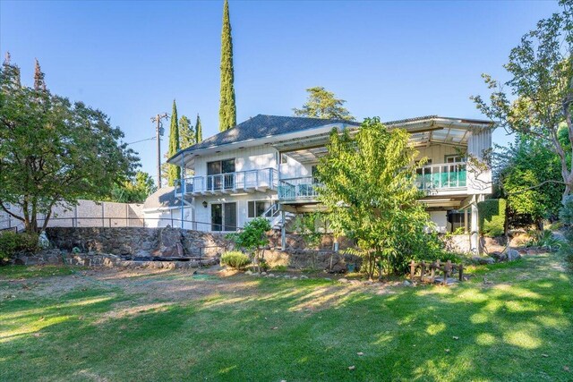 back of property featuring a balcony and a lawn