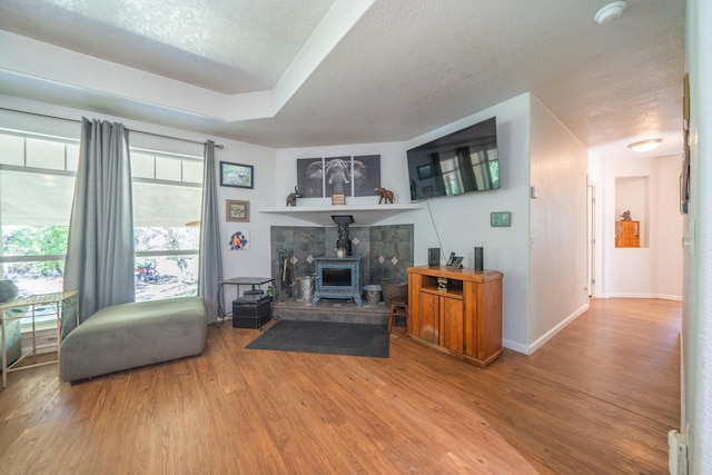 living room with a wood stove, wood-type flooring, and a textured ceiling