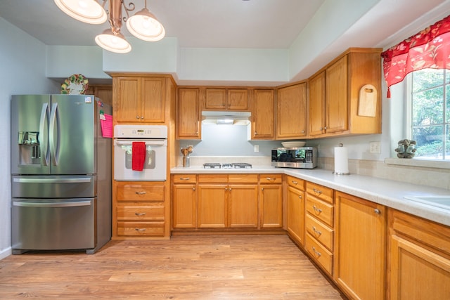 kitchen with pendant lighting, light hardwood / wood-style flooring, stainless steel appliances, and a chandelier