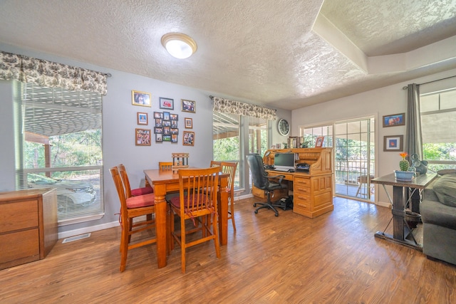 dining space featuring a textured ceiling, hardwood / wood-style flooring, and a wealth of natural light