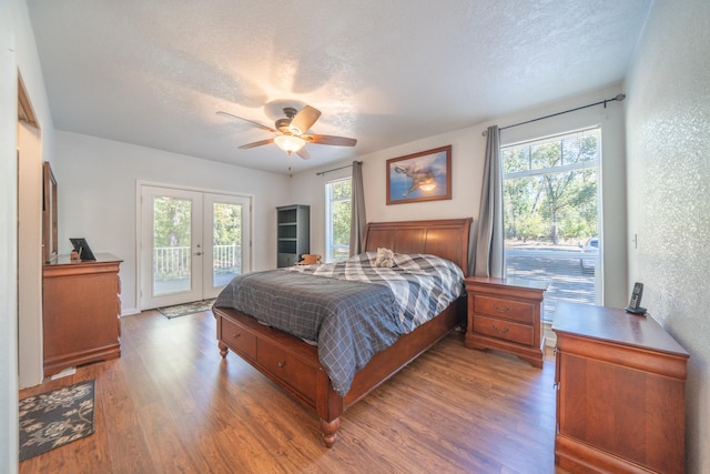 bedroom featuring wood-type flooring, multiple windows, ceiling fan, and a textured ceiling