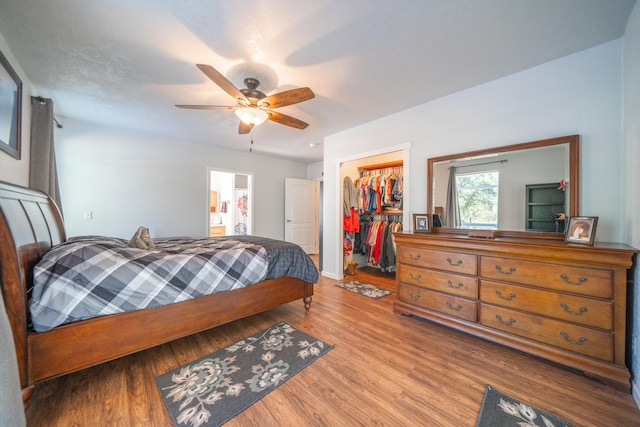 bedroom with ceiling fan, connected bathroom, light hardwood / wood-style flooring, a closet, and a spacious closet