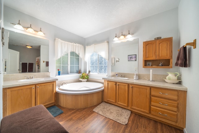 bathroom with vanity, hardwood / wood-style flooring, a bathtub, and a textured ceiling