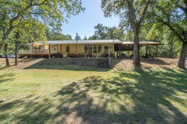 rear view of property featuring a yard, a carport, and a wooden deck