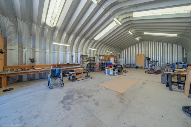 miscellaneous room featuring lofted ceiling, a workshop area, and concrete flooring